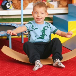 Zdjęcie uśmiechniętego dziecka siedzącego na podłodze.