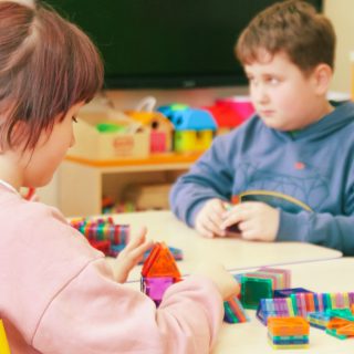 Zdjęcie dwójki dzieci bawiących się klockami przy stoliku.