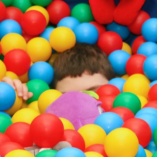 Zdjęcie dziecka w basenie z piłeczkami.